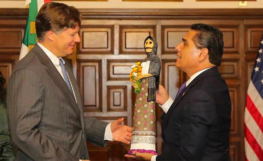 The governor, right, presents the ambassador with a traditional Day of the Dead figurine.