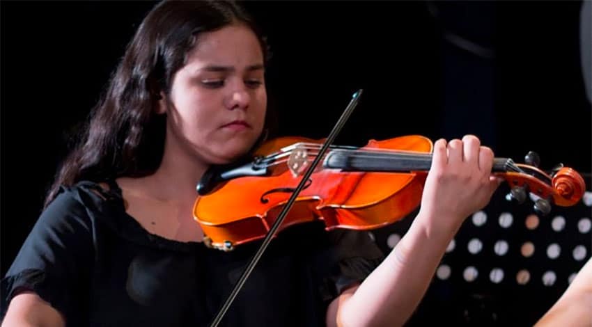 A young violinist performs during a DIME concert.