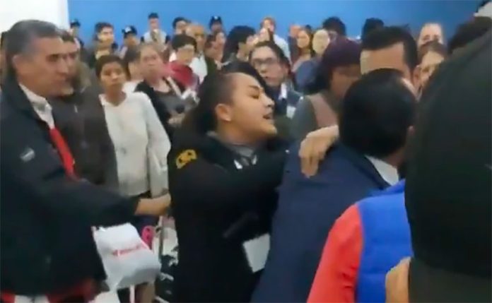 A security guard, center, breaks up a fight in Mexico City airport.
