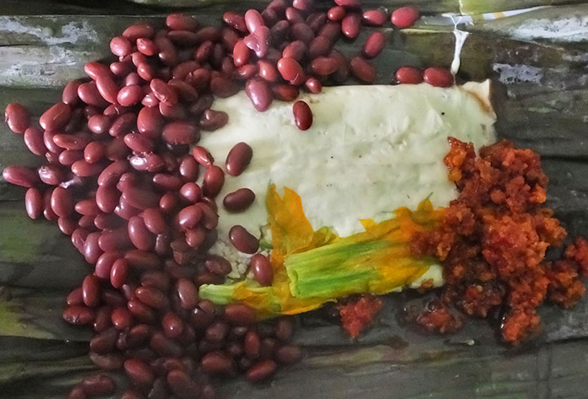 Cheese fondue on a banana leaf with pumpkin flowers, red beans and chorizo.