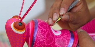 An artisan works on one of the pieces of whimsical folk art.