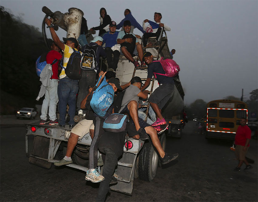 Migrants cling to a truck as they attempt to head into Mexico.