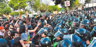 Police attempt to prevent masked protesters from entering the school, but were unsuccessful.