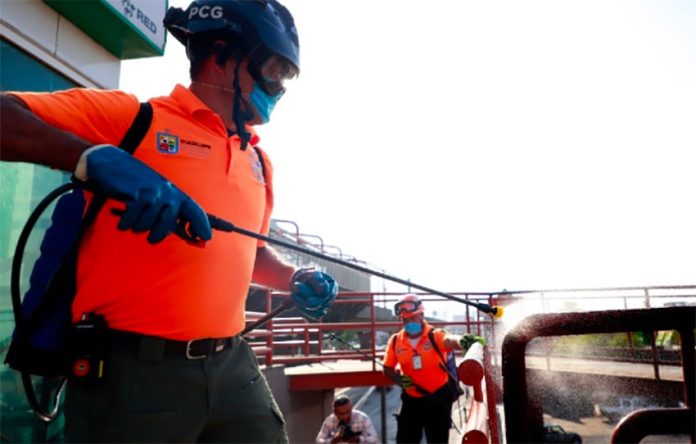 A worker at a transit station in Nuevo León sprays disinfectant.