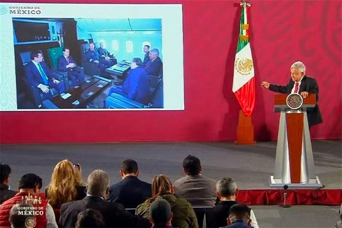 The president displays a photo of Peña Nieto and his cabinet aboard the presidential plane.