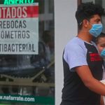 A couple walk past a store advising that it has sold out of face masks, thermometers and antibacterial gel.