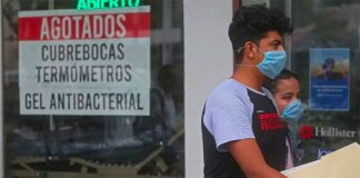 A couple walk past a store advising that it has sold out of face masks, thermometers and antibacterial gel.