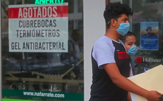A couple walk past a store advising that it has sold out of face masks, thermometers and antibacterial gel.