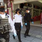 Masked security personnel on patrol in a shopping center.