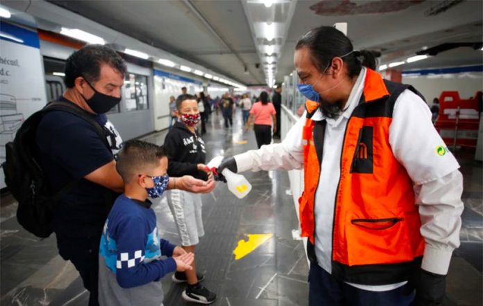 A Mexico City Metro worker dispenses hand sanitizer for passengers.