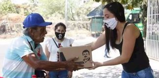 A woman hands out provisions bearing the image of the convicted drug trafficker.
