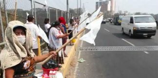 People line a highway in Guatemala on Saturday holding white flags to indicate they have no food. It may not be long before the flags appear in Mexico.