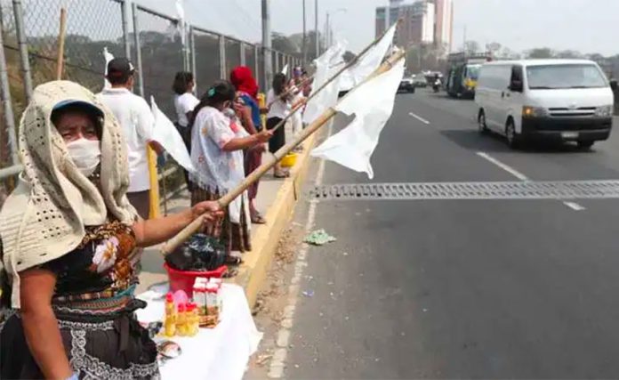 People line a highway in Guatemala on Saturday holding white flags to indicate they have no food. It may not be long before the flags appear in Mexico.