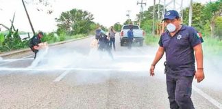Municipal workers sprinkle lime on a highway to disinfect vehicle tires.