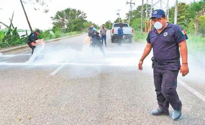 Municipal workers sprinkle lime on a highway to disinfect vehicle tires.