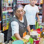 A woman attends to customers at a small Mexican corner store