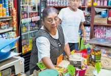 A woman attends to customers at a small Mexican corner store