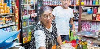 A woman attends to customers at a small Mexican corner store