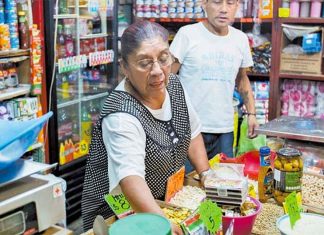 A woman attends to customers at a small Mexican corner store