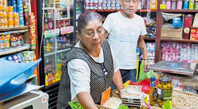A woman attends to customers at a small Mexican corner store
