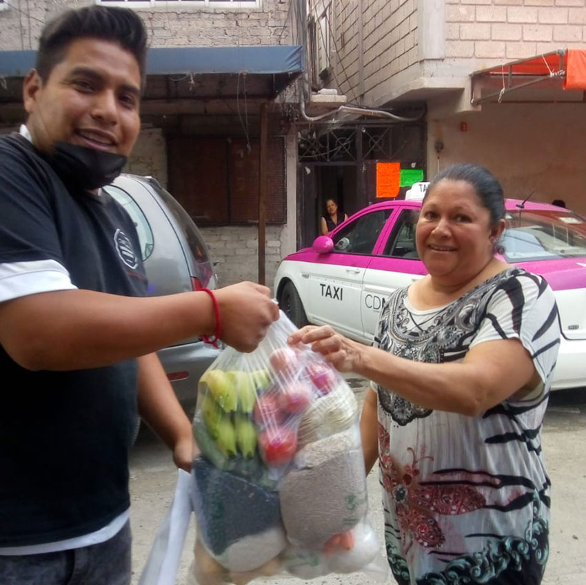 A volunteer, left, delivers a bag of supplies to a Mexico City resident.