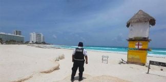 A police officer patrols an empty beach in Cancún