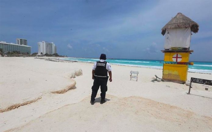 A police officer patrols an empty beach in Cancún