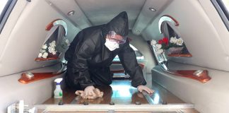 A funeral home worker disinfects a hearse.