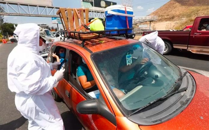 Health workers check the occupants of a vehicle heading out of Guadalajara on Friday.