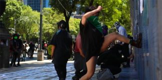 A woman drives her foot against a metal barrier outside the US Embassy Friday.