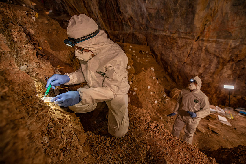 Assistant professor Mikkel Winther Pedersen from the University of Copenhagen sampling the cave sediments for DNA. 