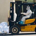 A forklift transports the body of a coronavirus victim