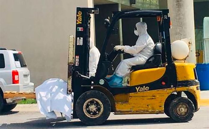 A forklift transports the body of a coronavirus victim