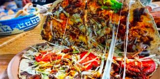 A Oaxacan tlayuda filled with a variety of ingredients.