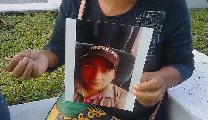 Andrade with a photo of her late husband, whose body was mistaken for that of another virus victim.