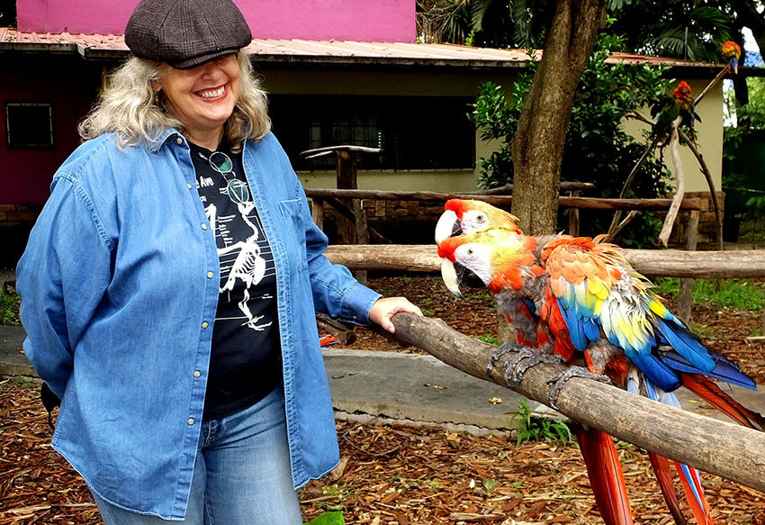 Parque Urbano manager Karina Aguilar with two rescued macaws.