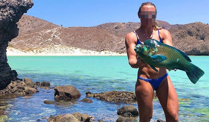 Woman with her parrotfish—at a closed beach in a protected area.