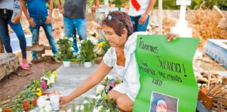 A woman places flowers at the grave of lynching victim Manrique Mezquita.