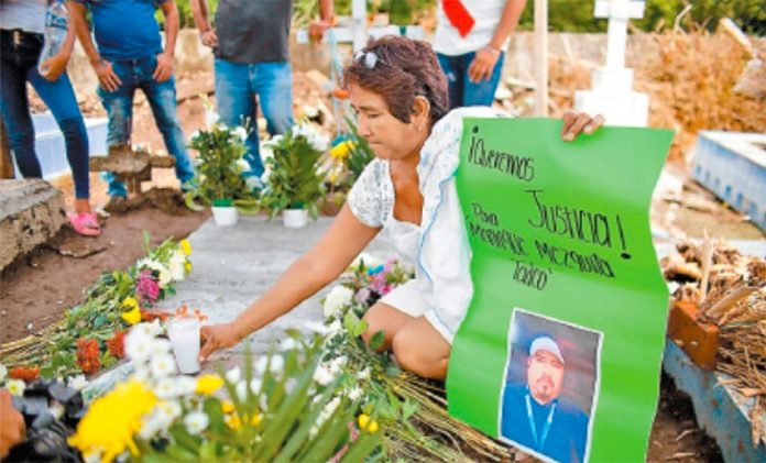 A woman places flowers at the grave of lynching victim Manrique Mezquita.