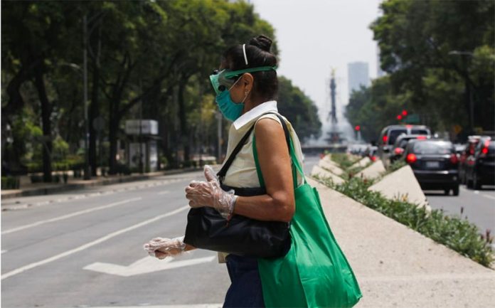With a mask, goggles and gloves, a woman crosses the street in Mexico City.