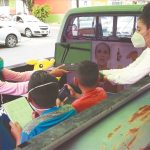 Tortillería owner Dalia Ávila passes a laptop to a student in the improvised classroom.