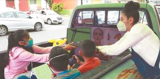 Tortillería owner Dalia Ávila passes a laptop to a student in the improvised classroom.
