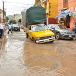 A vehicle encounters a pothole on a flooded Oaxaca city street.