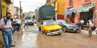 A vehicle encounters a pothole on a flooded Oaxaca city street.
