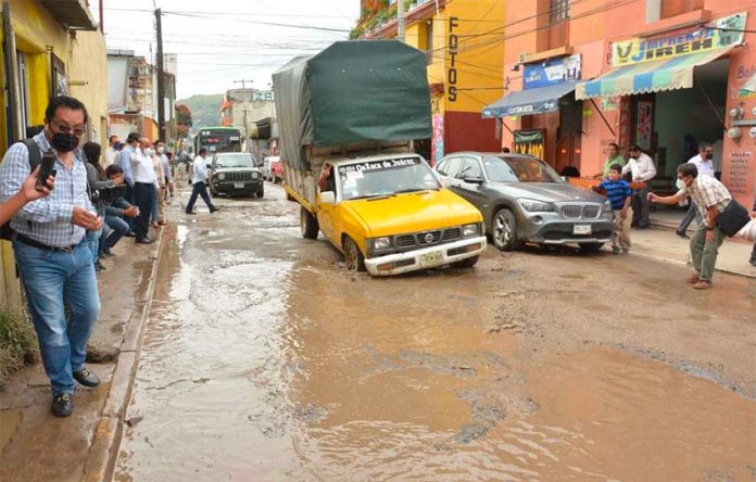 A vehicle encounters a pothole on a flooded Oaxaca city street.