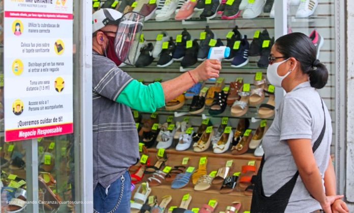 A customer's temperature is checked at a store in Guadalajara in July.