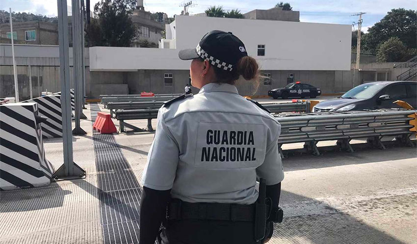 A member of the National Guard watches as hijackers collect tolls.