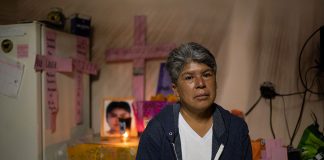 Lidia Florencio sits in front of the altar she put out for her daughter in her home.