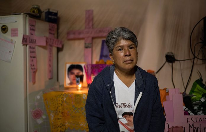 Lidia Florencio sits in front of the altar she put out for her daughter in her home.