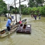 A man attempts to save a piece of furniture on a flooded road in Tabasco.